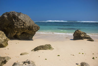 Rocks on beach against blue sky