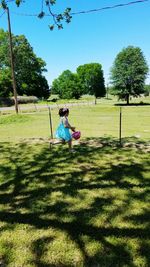 Girl playing on grass by trees against sky