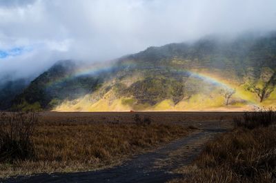 Scenic view of rainbow over land against sky