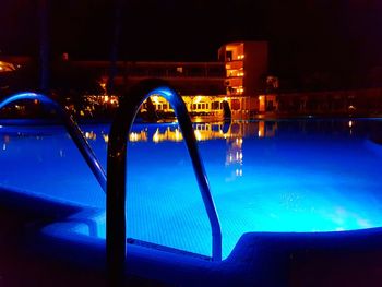 Swimming pool by river against sky at night