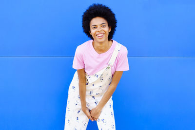 Young woman standing against blue background