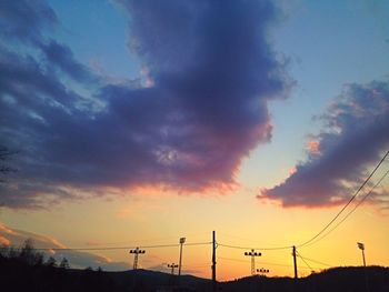 Low angle view of silhouette electricity pylon against sky