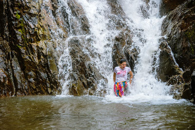Full length of girl splashing water in river