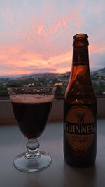 Close-up of beer glass on table against sky during sunset