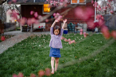 A little girl prepares to do handstand under a flowering tree at dusk