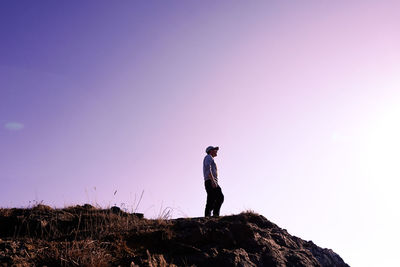 Rear view of man standing on mountain against sky