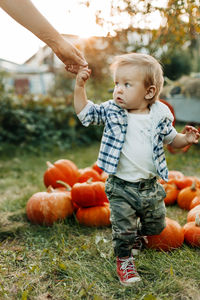 A happy baby is holding hands with his mother during the preparation for the halloween