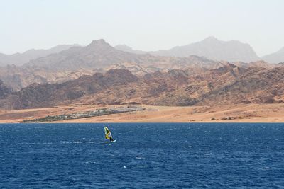 Scenic view of sea and mountains against clear sky