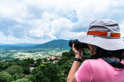 Rear view of woman photographing against sky