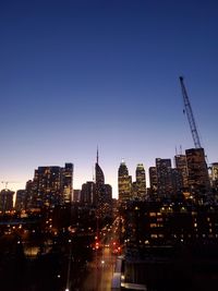 Illuminated buildings in city against clear sky