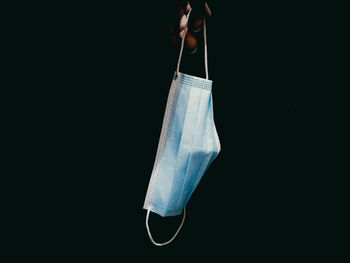 Close-up of hand holding umbrella against black background