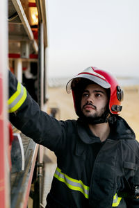 Tranquil worker wearing protective uniform and red hardhat operating inside fire truck
