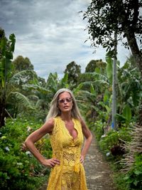 Portrait of smiling young woman standing against trees