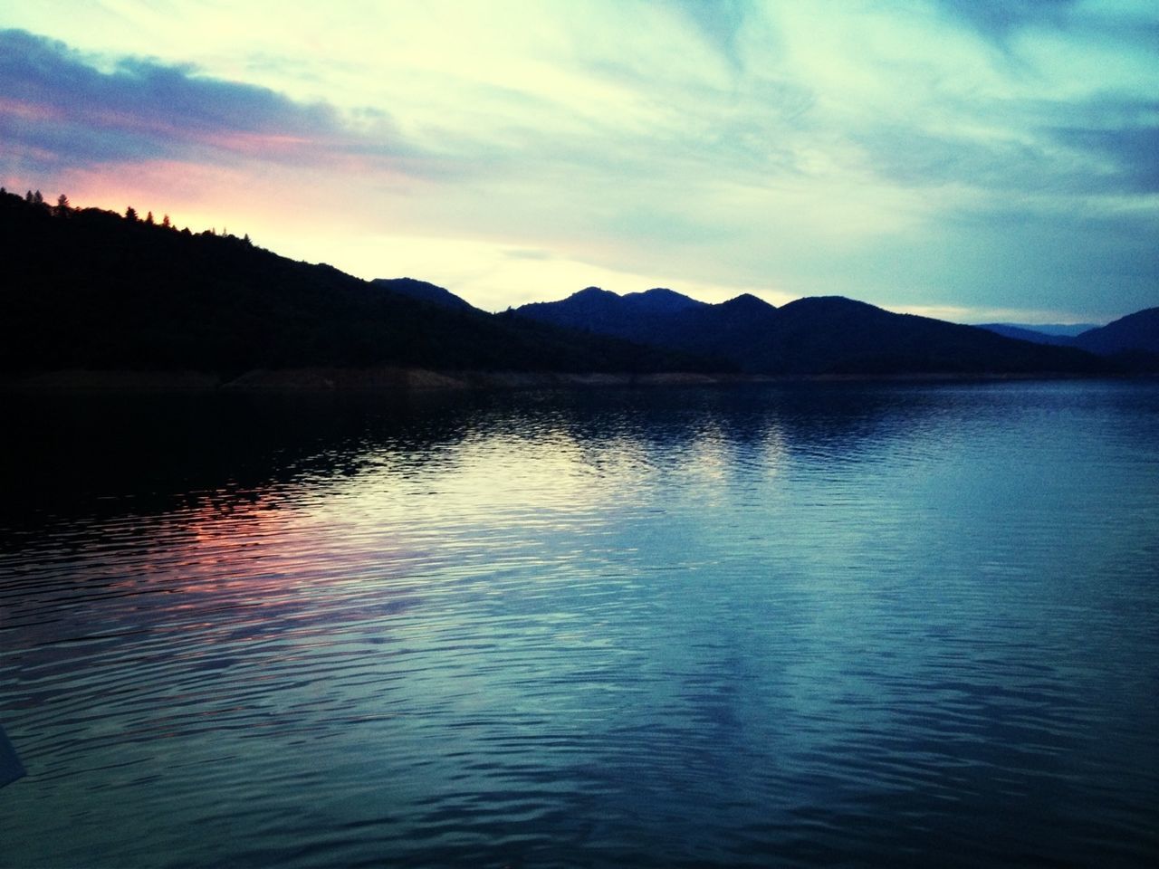 water, mountain, tranquil scene, scenics, tranquility, sky, lake, waterfront, beauty in nature, mountain range, reflection, silhouette, rippled, nature, cloud - sky, idyllic, sunset, cloud, calm, dusk