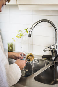 Woman washing dishes in kitchen sink