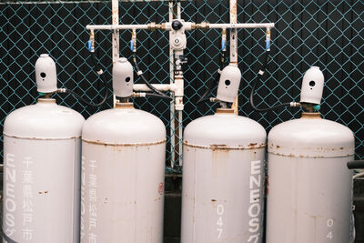 Close-up of white bottles on fence against wall