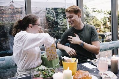 Woman surprising brother with gift while sitting at restaurant