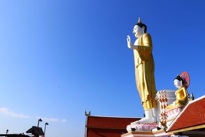 Low angle view of statue against building against blue sky