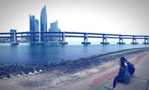 Bridge over river against sky in city