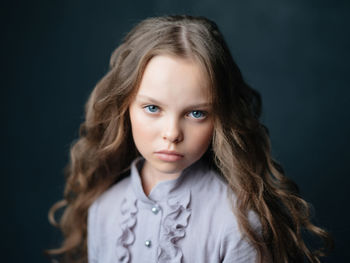 Portrait of cute girl against black background