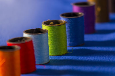Close-up of colorful spools arranged in row on blue fabric