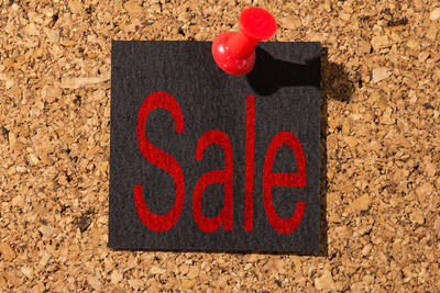 Close-up of paper with sale text pinned on bulletin board