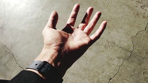 Close-up of hand wearing wristwatch against wall