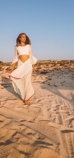 Woman on sand at beach against clear sky