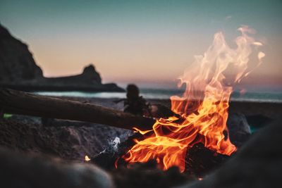 Campfire on beach against sky at sunset