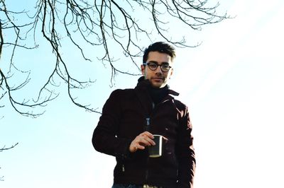 Portrait of young man standing against sky