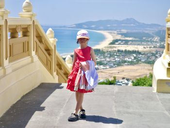 Full length of young woman standing against building