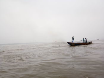 People in boat on sea against sky