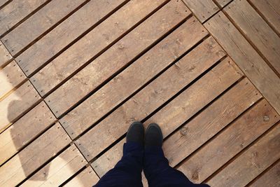 Low section of man standing on wooden floor