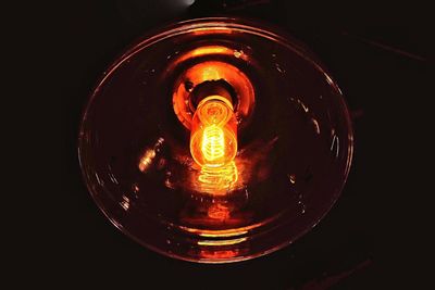 Low angle view of illuminated light bulb against black background