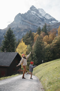 Rear view of woman a kid standing on field in front of a swiss mountain 