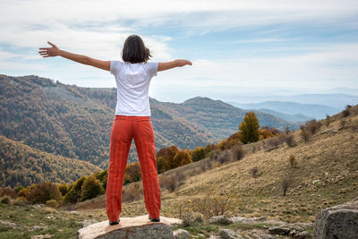 Rear view of woman standing against mountain and sky