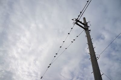 Low angle view of power lines against cloudy sky