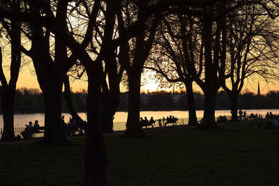 Silhouette trees by lake against sky during sunset