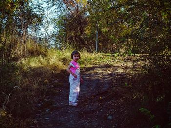 Full length portrait of little girl standing in forest