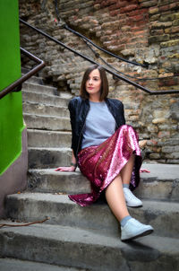 Young woman looking away while sitting on steps