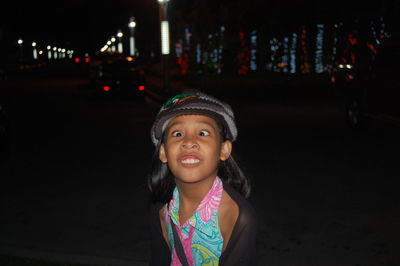 Playful girl making face on street in city at night
