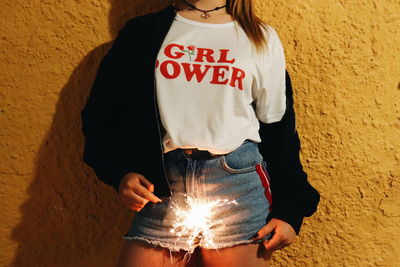 Midsection of woman standing against wall