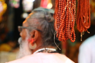 Close-up of rudraksha hanging at market stall with sadhu in background