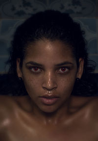 Close-up portrait of young woman with red eyes