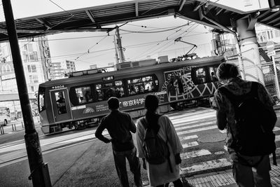 Rear view of people walking on train in city