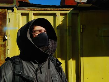Man wearing hood and mask standing outdoors