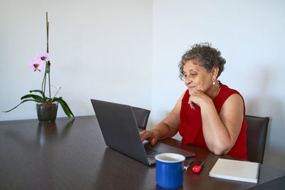 Young woman using mobile phone while sitting on table