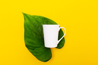 Close-up of coffee cup on yellow background