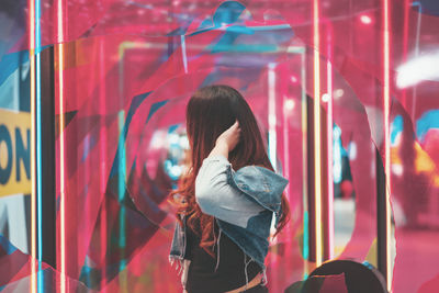 Rear view of woman looking through glass window