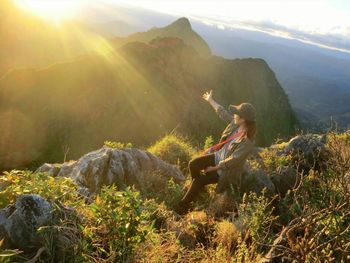 High angle view of hiker sitting on top of mountain during sunny day